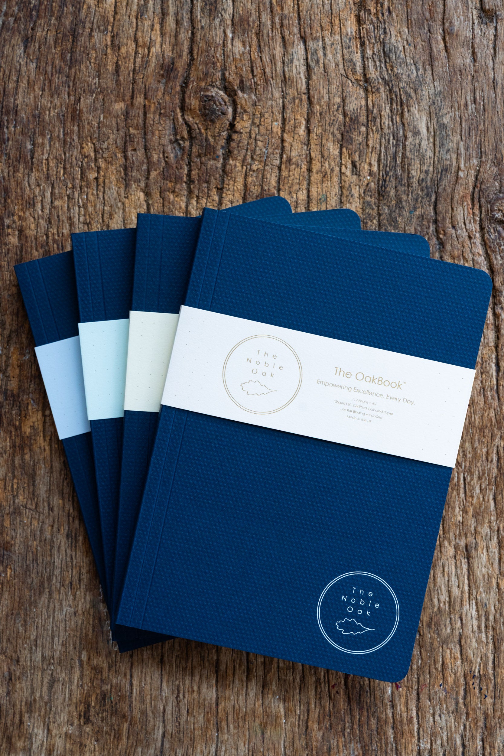 Set of blue notebooks with a brand label on a wooden surface