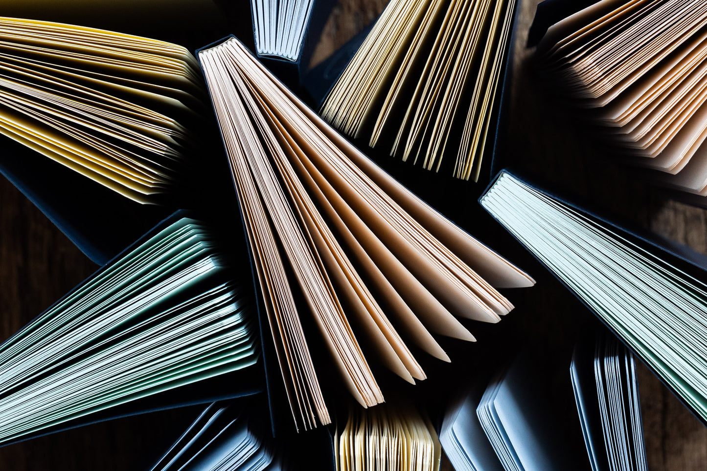 Open books with various colored pages on a reflective surface