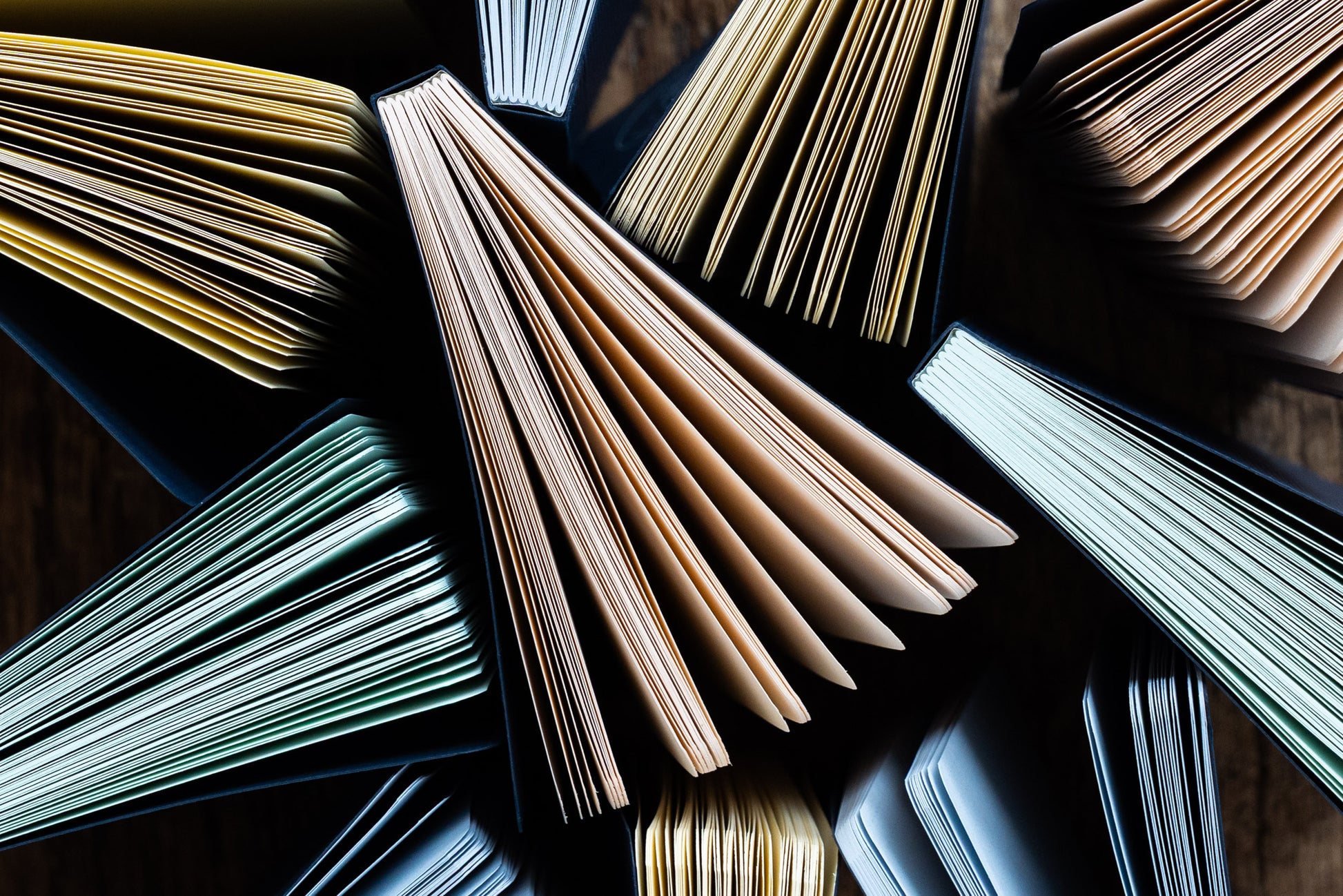 Open books with various colored pages on a reflective surface