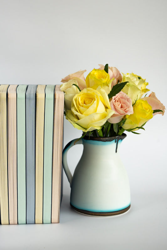 Vase with yellow and pink flowers next to a stack of The OakBook of all colours