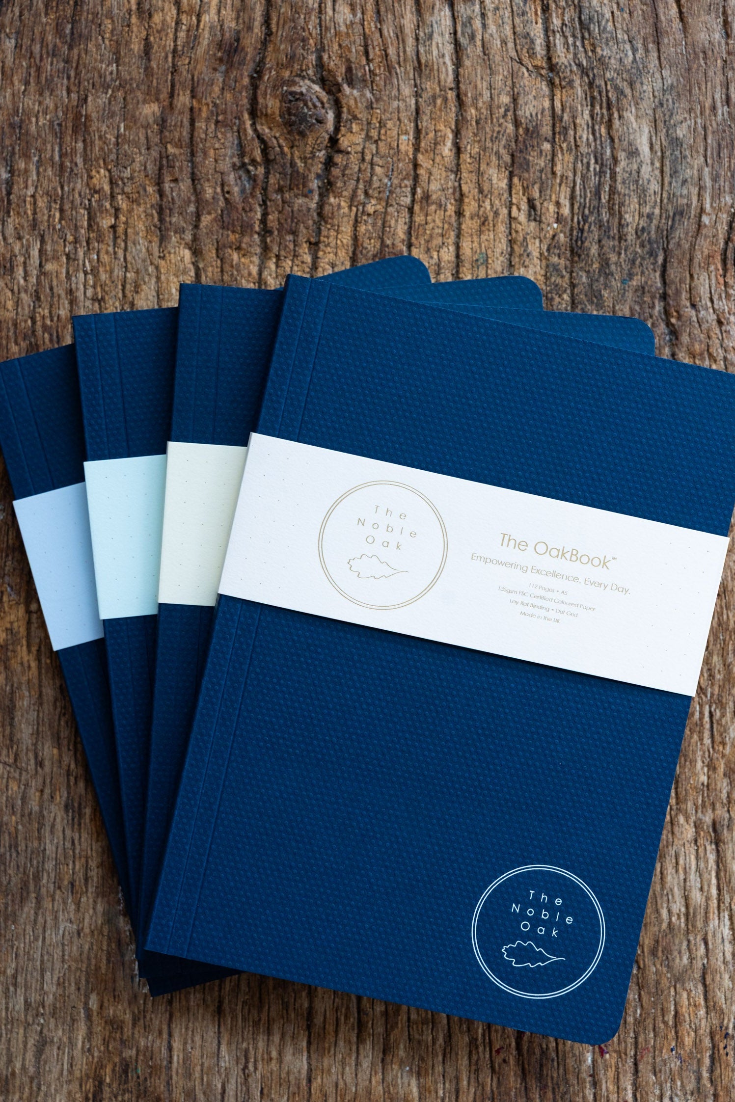 Set of blue notebooks with a brand label on a wooden surface